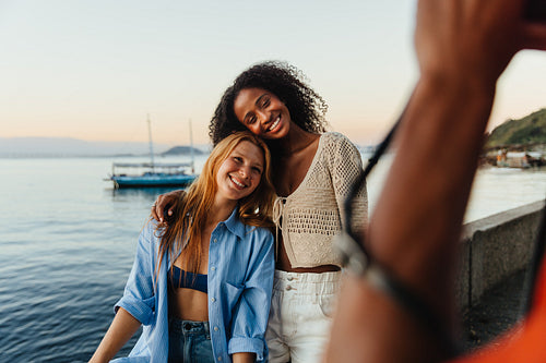 Joyful friends posing by the ocean at sunset