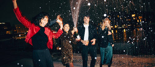 Group of friends celebrating with champagne outdoors during a festive night
