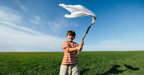 Boy waving white cloth in imaginative play outdoors
