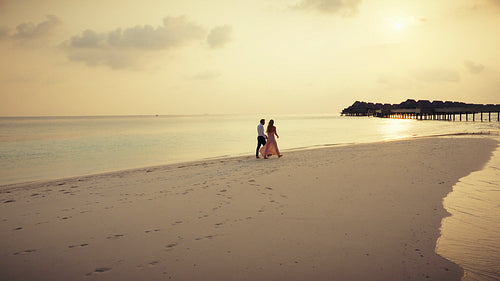 Couple enjoys a luxury family resort vacation on a stunning tropical beach at sunset