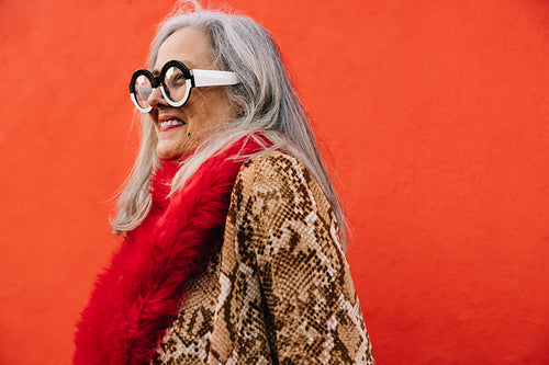 Cheerful elderly woman smiling happily against a red background