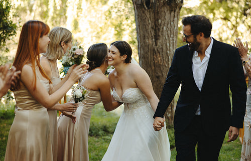 Joyful outdoor wedding celebration with bride, groom, and bridesmaids in elegant attire