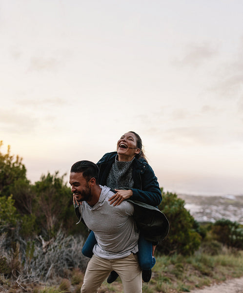 Couple enjoying piggyback ride in countryside