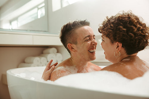 Carefree young queer couple having a romantic bubble bath at hom
