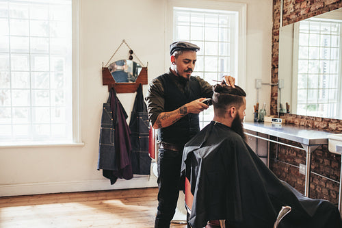 Male barber giving client haircut  