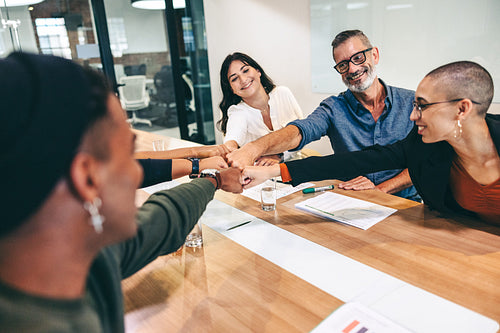 Successful businesspeople bringing their fists together in a boardroom