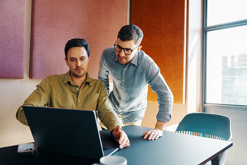 Two men sharing ideas while working together in a modern office setting