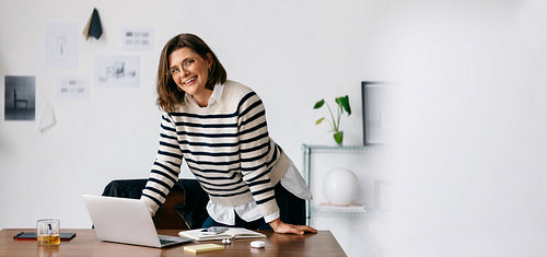 Creative woman working at a laptop in the office with business documents on her desk