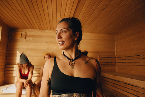 Middle-aged woman enjoys sauna session with friends in warm space
