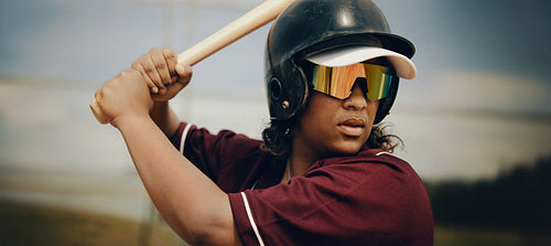 Confident female professional baseball batter preparing for a powerful swing