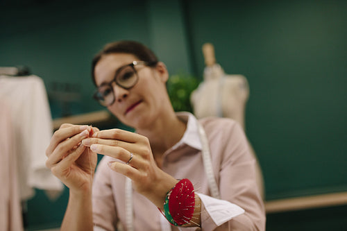Female threading the needle at fashion studio