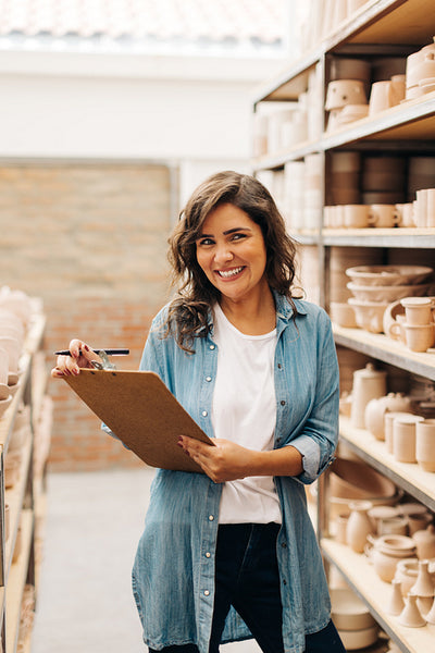Successful female ceramist smiling at the camera in her shop