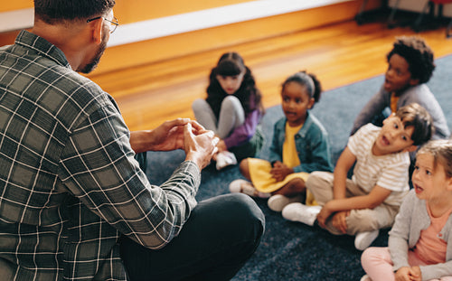 Educator teaches an elementary school class. Man talking in front of a group of children