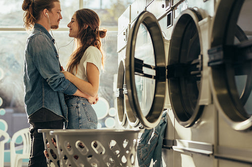 Smiling couple standing together holding each other in the laundry room