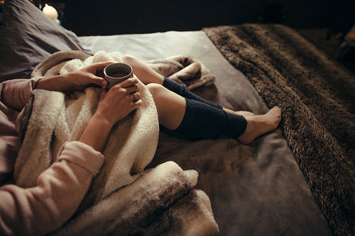 Woman lying on bed with a cup of coffee