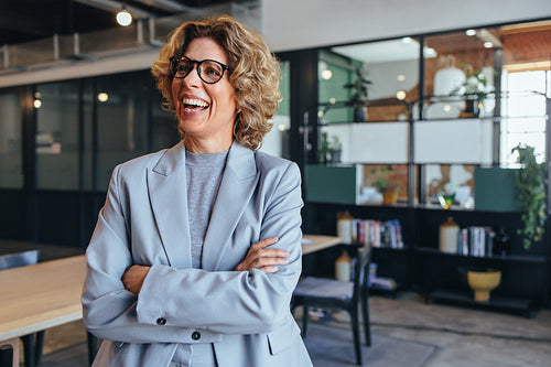 Mature business woman smiling and standing with crossed arms