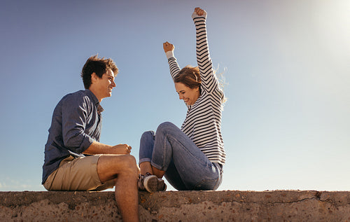 Happy couple having fun sitting on a sea wall