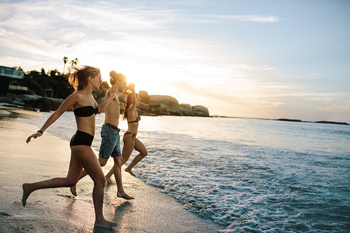 Group of happy friends running to the sea