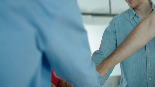 Coworkers celebrate team success with a hands-in huddle in a bright office