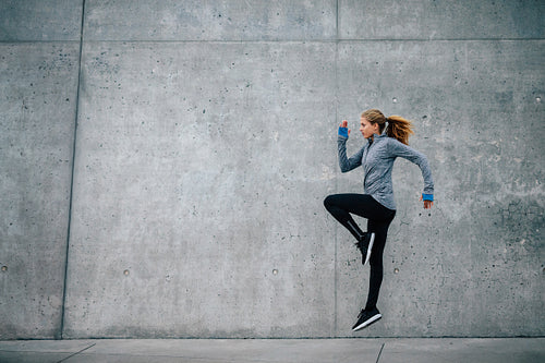 Young woman running and jumping on city street
