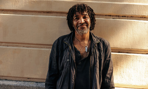 Cheerful homeless man looking at the camera outdoors