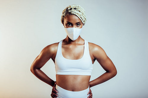 Fitness woman with face mask standing on white background