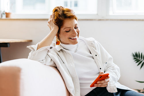 Freelance professional smiling in a modern co-working space whiling looking at her smartphone