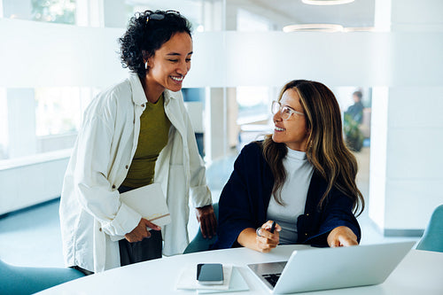 Two women share ideas during a work meeting