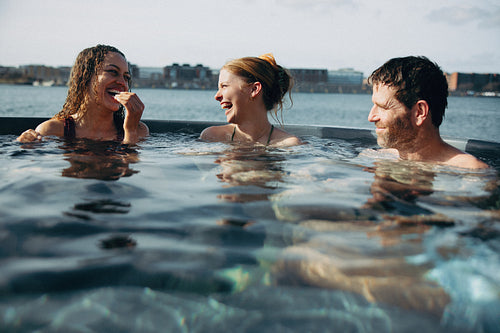 A wellness retreat shows people laughing together in an outdoor spa.