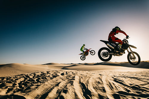 Motorcyclists jumping over dunes
