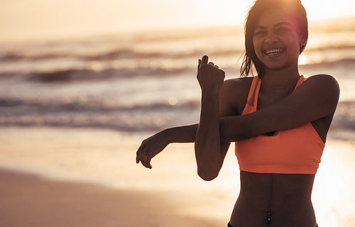 Smiling woman stretching arms at the beach
