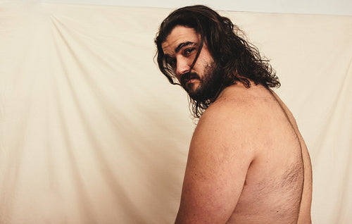 Shirtless man with long hair looking at the camera