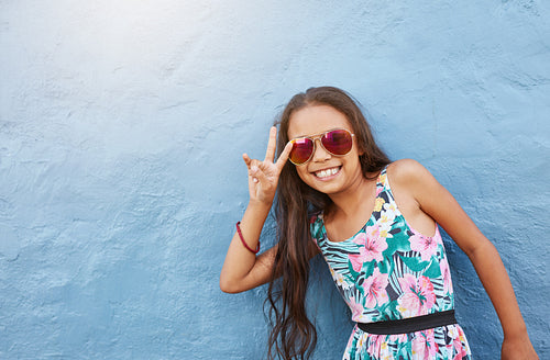 Cute little girl with sunglasses gesturing peace sign