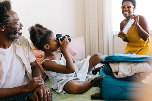 Exciting family vacation: Mom posing for a photo with flight ticket, daughter capturing happy moments