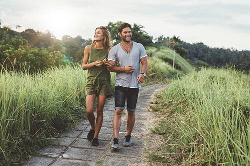 Young couple in love walking on pathway through grass field