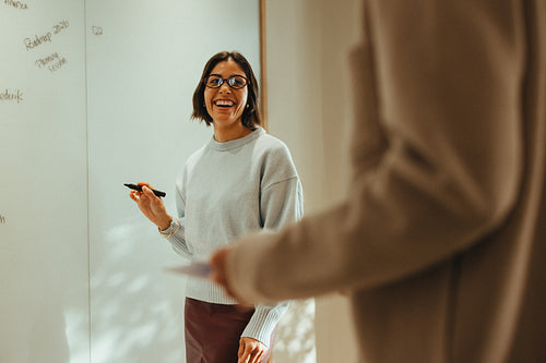 Woman guides business discussion at the whiteboard in an office workshop