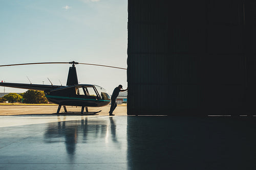Pilot opening the helicopter hangar door.