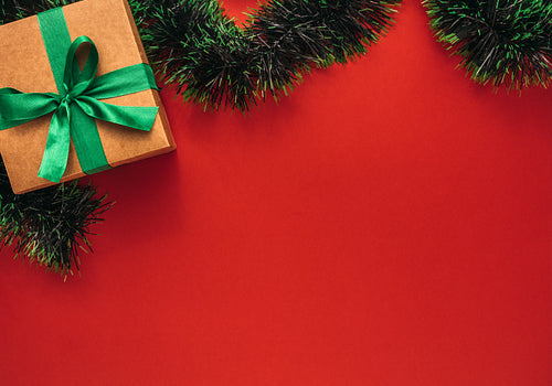 Flat lay of gift box with garland on red background