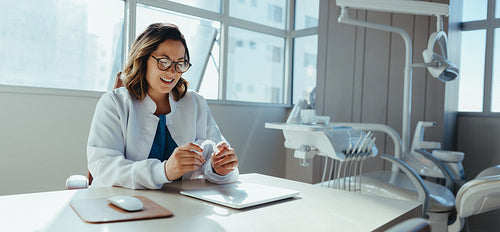 Female dentist reviews dental aligners at office desk