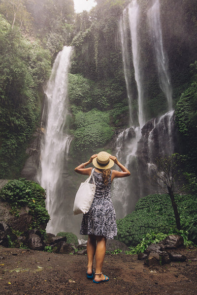 Female tourist admiring waterfall in rain forest