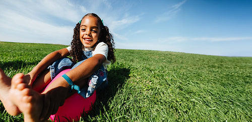 Girl enjoying carefree summer play in open grassy field
