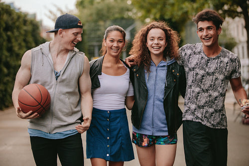 Four young friends walking together and smiling