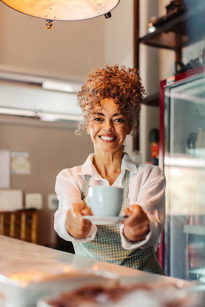 Confident barista serving a customer in her cafe