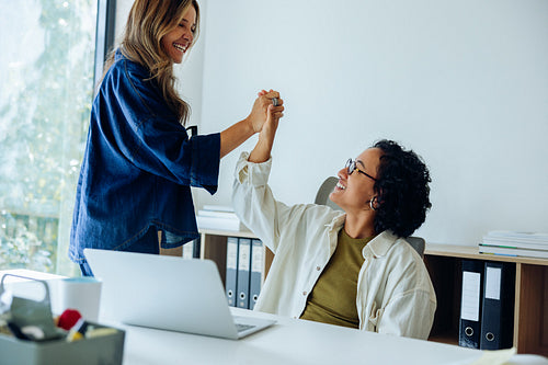Two coworkers celebrate a win at the office
