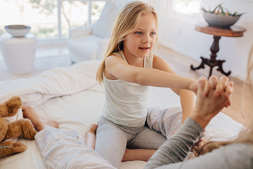 Beautiful little girl with her mother on bed