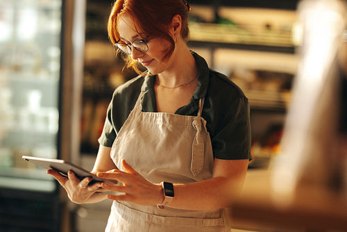Cheerful supermarket owner using a digital tablet in her shop