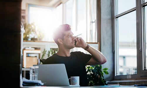 Businessman sitting at his office talking on cell phone