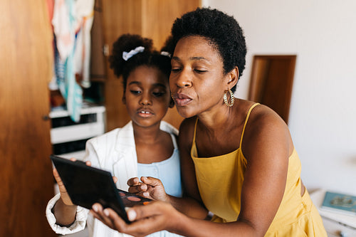 Black girl makeup: Mother and daughter choosing the perfect makeup shade from a palette