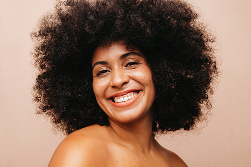 Pretty woman with Afro hair smiling at the camera in a studio