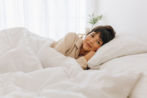 Woman lying on bed at home